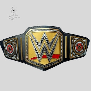 May include: A black and gold wrestling championship belt with the WWE logo in the center. The belt features a gold center plate with the WWE logo and the words "Undisputed Champion". The side plates have the WWE logo in red.