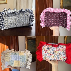 May include: Four decorative pillows with ruffled edges. One pillow features a blue floral pattern with a navy and white gingham ruffle. Another has a pink floral pattern with a pink and white gingham ruffle. The other two pillows have floral and patchwork designs with cream and red ruffles.