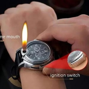 May include: A silver watch with a black face and a lighter built into the side. The lighter has a flame coming out of the side. The watch has a black leather band. The text "ignition switch" is written on the image.