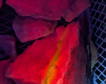 May include: Close-up of a red brick with a yellow streak running through it. The brick is illuminated with a pink and blue light, creating a vibrant and colourful effect.