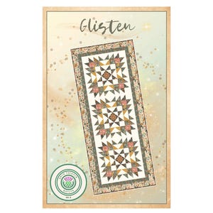 May include: A rectangular quilt pattern with the word "Glisten" in cursive script. The quilt features star and floral patterns in cream, gold, and pink. The design is framed by a border with floral and leaf patterns. A circular logo is in the lower left corner.