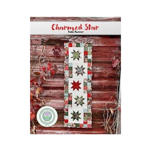 Puede incluir: Un camino de mesa acolchado rojo, verde y blanco con un patrón de estrellas. El camino de mesa está colgado en una pared de madera roja. El texto "Charmed Star Table Runner" está en la parte superior de la imagen.