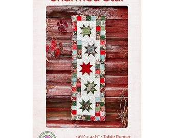 May include: A Charmed Star table runner pattern featuring a vertical arrangement of five star blocks on a white background, surrounded by a border of small multi-coloured squares. The finished size is 14.5 inches by 44.5 inches for beginners.