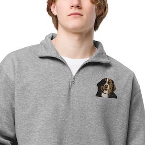 Könnte beinhalten: Ein grauer Pullover mit einem Viertelreißverschluss zeigt ein gesticktes Bild eines Berner Sennenhundes mit braunem und weißem Fell.