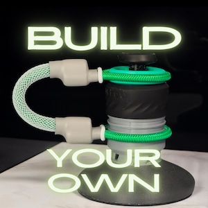 May include: A modular device with a black base and a central grey and black cylindrical body. It features two bright green braided cords attached to grey connectors, with the text BUILD YOUR OWN displayed in glowing light green letters.
