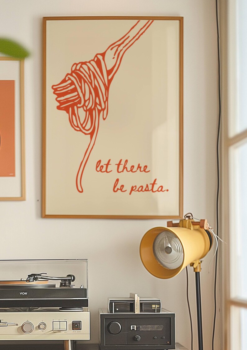 May include: A framed print with a red illustration of a fork with spaghetti on it. The text "let there be pasta." is written in red below the illustration.