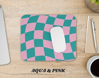 May include: A teal and pink checkered mouse pad with a wavy pattern. The mouse pad has the text "AQUA & PINK" printed on it. The text "* PATTERN PLACEMENT MAY VARY ON FINISHED PRODUCT" is printed below the main text.