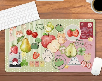 Puede incluir: Un mousepad rectangular grande con un diseño caprichoso que presenta frutas de dibujos animados, animales y elementos de inspiración japonesa. El diseño incluye fresas, peras, gatos, ranas y un sello con texto japonés. El mousepad está sobre un escritorio de madera.