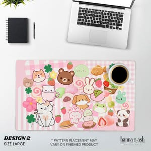 May include: A pink desk mat with a kawaii design featuring cartoon animals, sweets, and strawberries. The mat has a gingham and striped pattern. A cup of coffee, a laptop, a notebook, and a pen are on the desk.