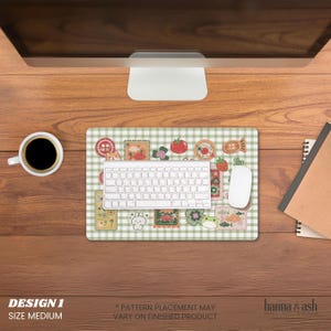 Pu&ograve; includere: Un tappetino per mouse di medie dimensioni con un motivo a quadri verdi e bianchi, con varie simpatiche illustrazioni. Una tastiera e un mouse bianchi sono sul tappetino, con una tazza di caff&egrave; e un taccuino nelle vicinanze. Testo "DESIGN 1 SIZE MEDIUM".