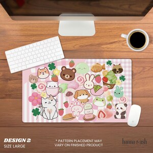 Pu&ograve; includere: Un grande tappetino per mouse rosa con un design kawaii con vari animali dei cartoni animati, cibi e accenti di trifoglio. Il tappetino per mouse ha uno sfondo a righe e il testo "DESIGN 2 SIZE LARGE".