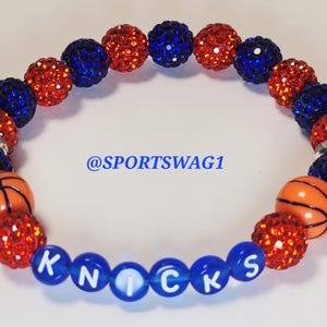 Handmade sparkly bracelet set featuring orange and blue crystal-encrusted beads with mini basketball charms and "NY KNICKS" letter beads, designed for fans of the New York Knicks basketball team perfect for game day, team spirit, and gifting. Custom colors available.