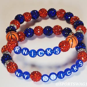 Handmade sparkly bracelet set featuring orange and blue crystal-encrusted beads with mini basketball charms and "NY KNICKS" letter beads, designed for fans of the New York Knicks basketball team perfect for game day, team spirit, and gifting. Custom colors available.