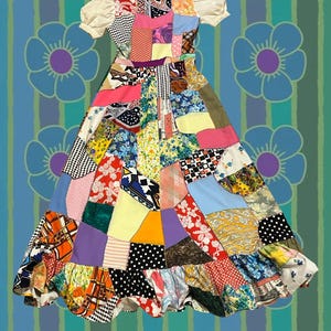 May include: A colourful patchwork dress with a mix of patterned fabrics, including floral, polka dot, and geometric designs. The dress has short, puffed sleeves and a ruffled hem. The background features a blue floral pattern.