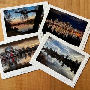 May include: Four different photographs of the Vancouver skyline, each with a different time of day and weather. The first photo shows a sunset over the city with a large tree in the foreground. The second photo shows the city at night with the lights of the buildings reflected in the water. The third photo shows the city during the day with a cloudy sky. The fourth photo shows the city at dusk with a clear sky.