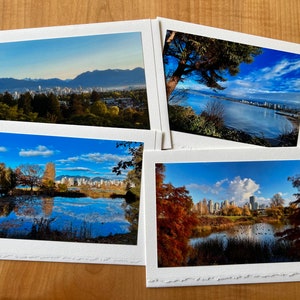 May include: Four white framed photographs of a city skyline with mountains in the background, a lake with trees and a city skyline in the background, a lake with trees and a city skyline in the background, and a lake with trees and a city skyline in the background.