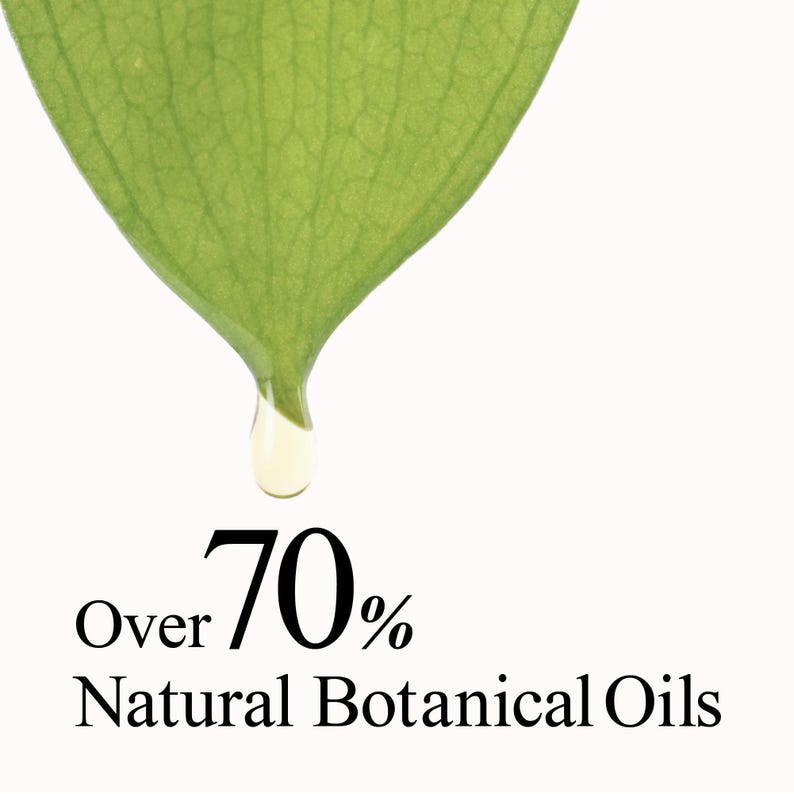 Op de afbeelding: Een levendig groen blad met zichtbare nerven waar een enkele heldere druppel vloeistof vanaf valt. Onder het blad staat de zwarte tekst: Over 70% Natural Botanical Oils. De compositie is geplaatst tegen een effen witte achtergrond.