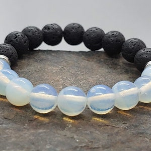 May include: A bracelet made with black lava rock beads and white opal beads. The bracelet is made with stretchy string.