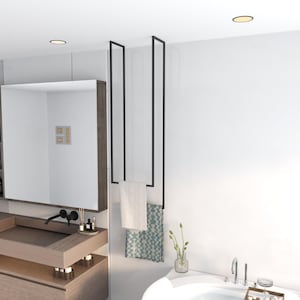 May include: A black metal towel rack with two bars hanging from the ceiling. Two towels are hanging on the rack, one white and one blue with a geometric pattern.