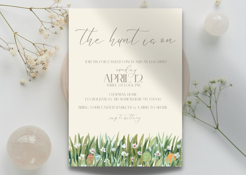 K&ouml;nnte beinhalten: Eine beige Einladungskarte mit dem Text "the hunt is on" in kursiver Schrift. Die Einladung ist f&uuml;r ein Osteressen und eine Ostereiersuche am Sonntag, den 12. April um 15:00 Uhr. Die Adresse lautet 123 Holdaway Rd Somewhere, UT 67000. Die Einladung bittet die G&auml;ste, ihre Osterk&ouml;rbe und ein Gericht zum Teilen mitzubringen. Der untere Teil der Karte zeigt eine Aquarell-Illustration von gr&uuml;nem Gras, wei&szlig;en Blumen und bunten Ostereiern.