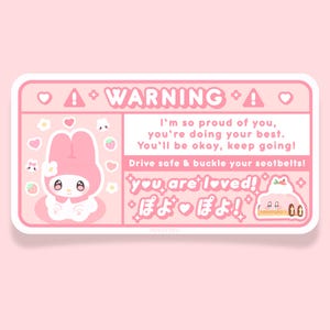 May include: Pink warning sticker with a cartoon bunny rabbit, hearts, and strawberries. The text reads "WARNING! I'm so proud of you, you're doing your best. You'll be okay, keep going! Drive safe & buckle your seatbelts! you are loved! ぽよ! ぽよ!"