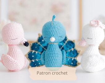 Puede incluir: Tres animales de peluche tejidos a crochet: un flamenco rosa, un pavo real azul y un cisne blanco. El pavo real tiene una cola azul y dorada. La leyenda dice "Patron crochet".