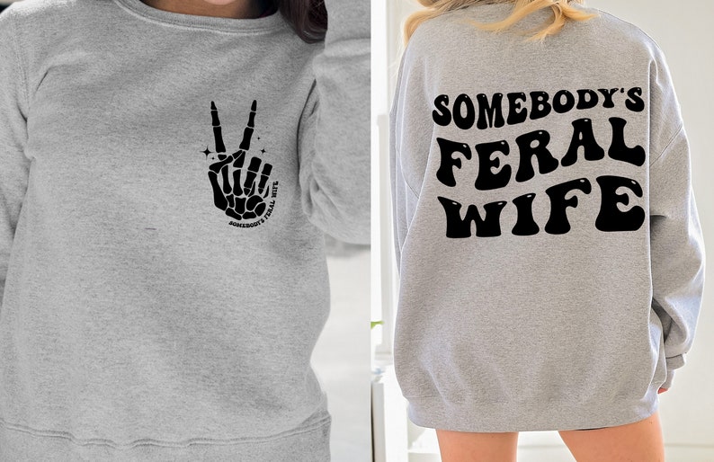 May include: Gray sweatshirt with a skeleton hand making a peace sign and the text "Somebody's Feral Wife" on the front. The back of the sweatshirt has the text "Somebody's Feral Wife" in a retro font.