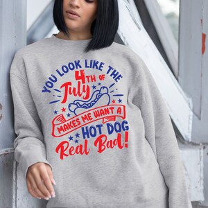 May include: A light gray sweatshirt with the text "YOU LOOK LIKE THE 4TH OF JULY MAKES ME WANT A HOT DOG Real Bad!" in red and blue. The design includes a hot dog and stars.