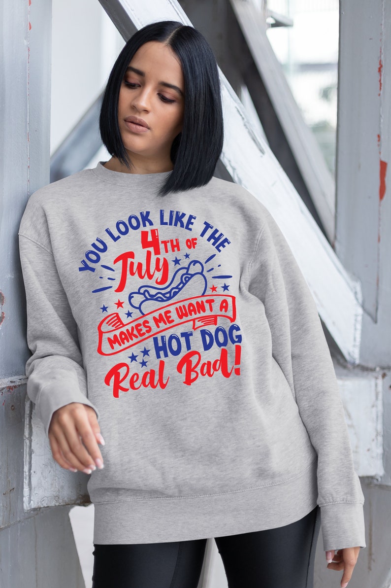 May include: A light gray sweatshirt with the text "YOU LOOK LIKE THE 4TH OF JULY MAKES ME WANT A HOT DOG Real Bad!" in red and blue. The design includes a hot dog and stars.