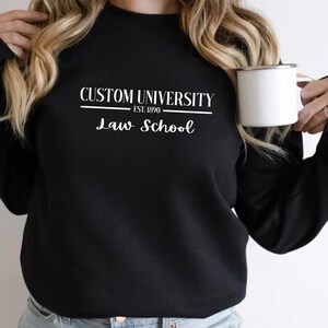 May include: Black sweatshirt with white text that reads "Custom University Est. 1890 Law School".