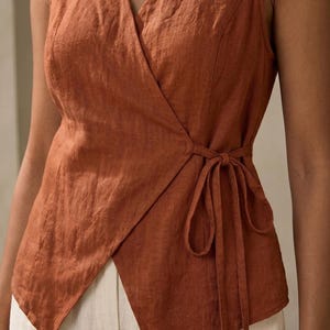 A woman wearing a brown sleeveless top with a tie at the waist.