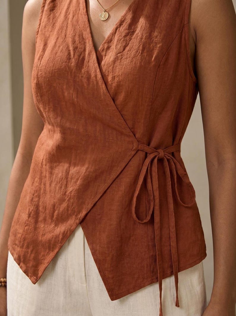 A woman wearing a brown sleeveless top with a tie at the waist.