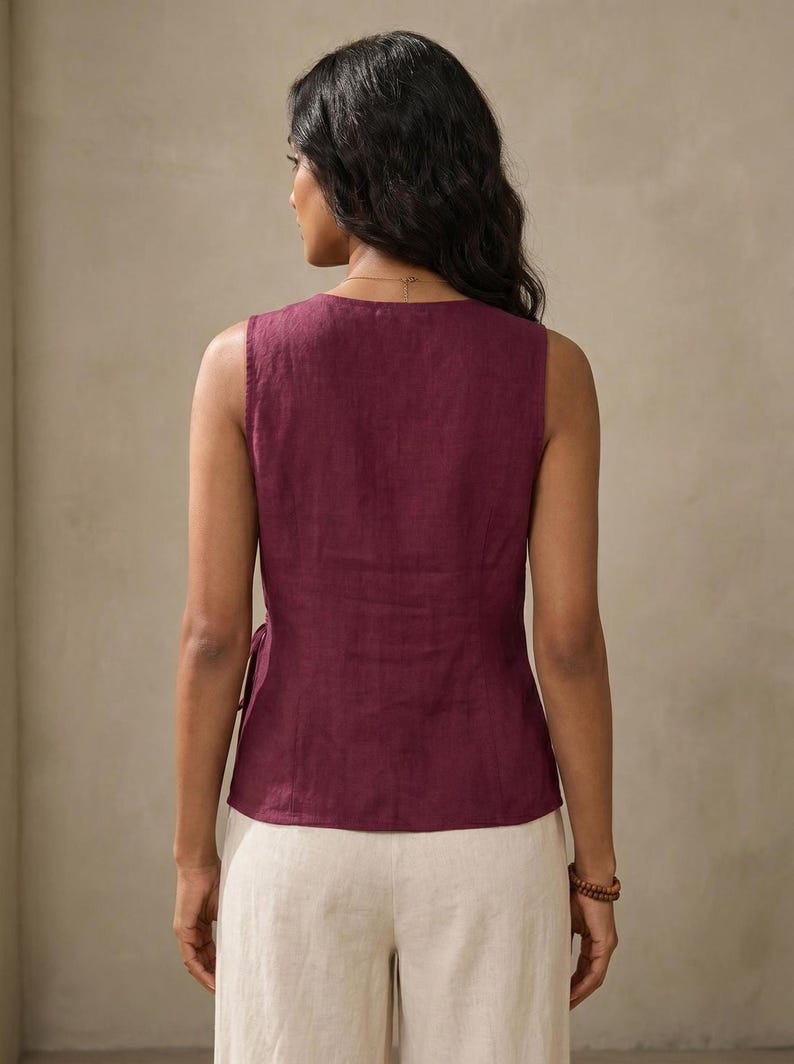 A woman wearing a maroon sleeveless top and white pants is facing away from the camera, with her back to the viewer.