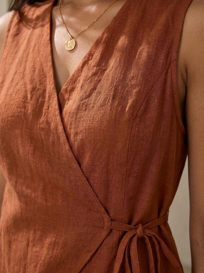 A close-up view of a woman wearing a brown wrap dress with a gold necklace.
