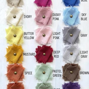 May include: A color chart featuring samples of fabric in various shades, including white, coral, navy blue, sand, magenta, and others. Each fabric swatch is adorned with a gold-colored stud and labeled with its corresponding color name.