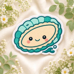 May include: An embroidered patch featuring a cartoon-style clam with a light beige center, a smiling face with pink cheeks, and a scalloped teal shell border. The design includes a small teal water splash detail at the bottom right corner.