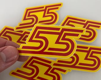 May include: Multiple yellow and red stickers with the number 55 printed on them. The stickers are stacked on top of each other.