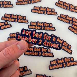 May include: Multiple stickers with the text "not bad for a number 2 driver." The stickers are blue with yellow and red outlines. The text is in a bold, rounded font.
