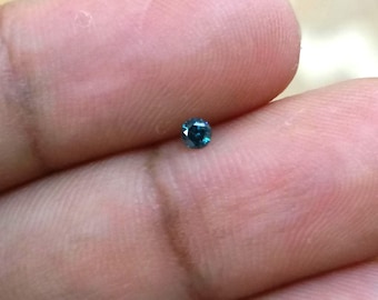 Pode incluir: Uma pequena gema redonda de cor azul-esverdeada.