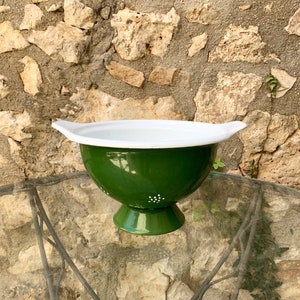 Op de afbeelding: Een groene emaille vergiet met een witte rand en witte stippen. De vergiet heeft twee handvatten en een voet.