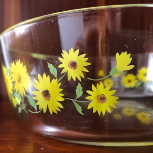 May include: A clear glass baking dish with a yellow and green sunflower design.