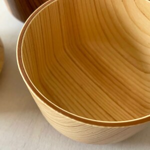 May include: A wooden bowl with a natural wood finish. The bowl has a smooth, rounded interior and a slightly flared rim.