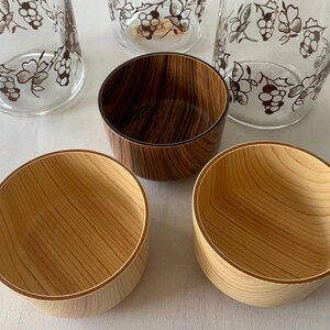 May include: Four wooden bowls, two with a natural wood finish and two with a dark wood stain. The bowls have a light brown rim.