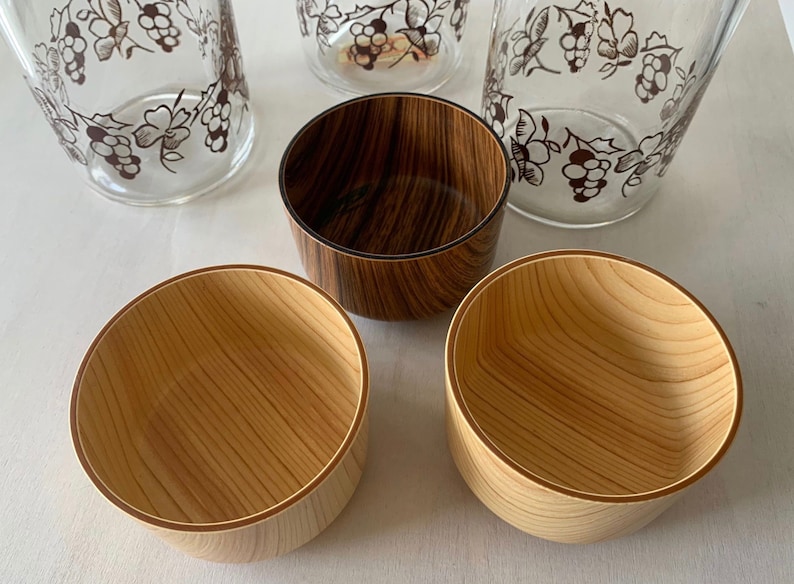 May include: Four wooden bowls, two with a natural wood finish and two with a dark wood stain. The bowls have a light brown rim.