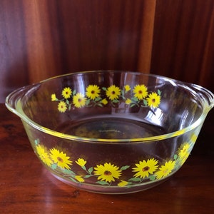 May include: A clear glass baking dish with yellow and green floral design. The dish has two handles on the sides.