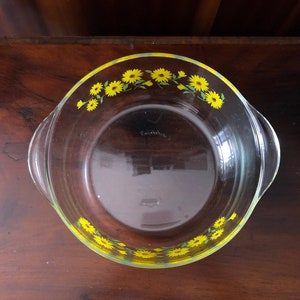 May include: A clear glass baking dish with a yellow and green floral design around the rim.