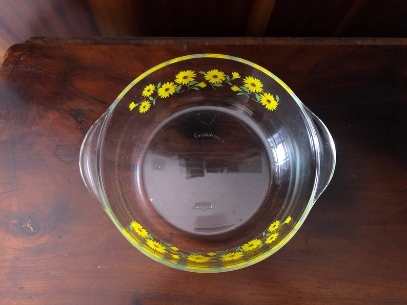 May include: A clear glass baking dish with a yellow and green floral design around the rim.