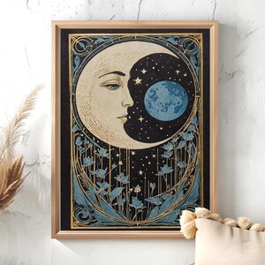 Puede incluir: Una impresión enmarcada de una luna creciente con el rostro de una mujer y un planeta azul en su interior. La luna está rodeada de un diseño floral y estrellas sobre un fondo negro.