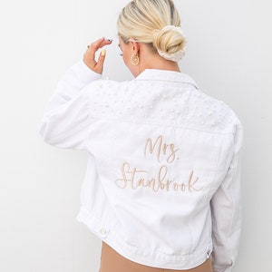 Personalized bridal denim jacket. Made from soft denim and decorated with faux pearls for a chic look. White jean jacket custom embroidered with your name. Perfect to wear for an engagement photoshoot.