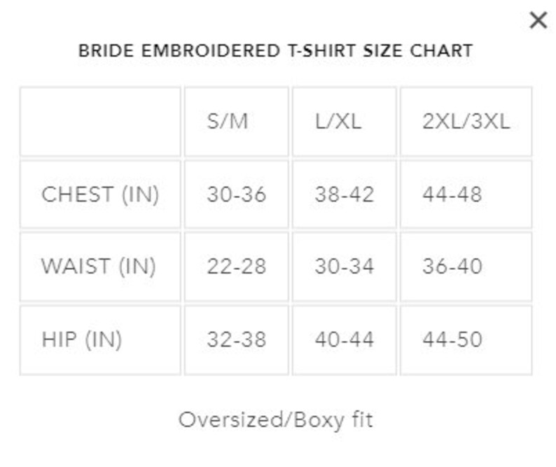 May include: Bride embroidered t-shirt size chart with measurements in inches for chest, waist, and hip. Sizes include S/M, L/XL, and 2XL/3XL. The chart indicates an oversized/boxy fit.